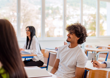 Schüler sitzen im Klassenraum und hören einem Lehrer zu